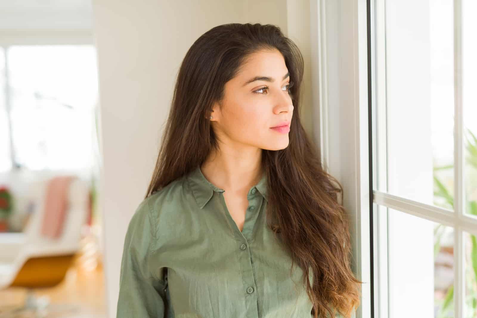 beautiful woman thinking while standing by the window