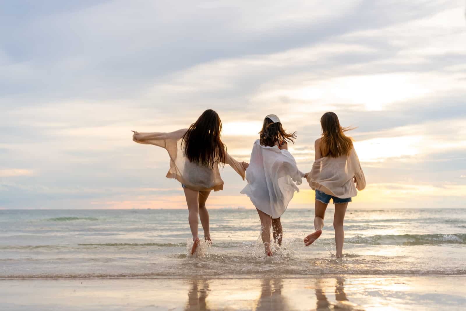 Group of Young Asian woman in walking and playing together on tropical beach at summer sunset.