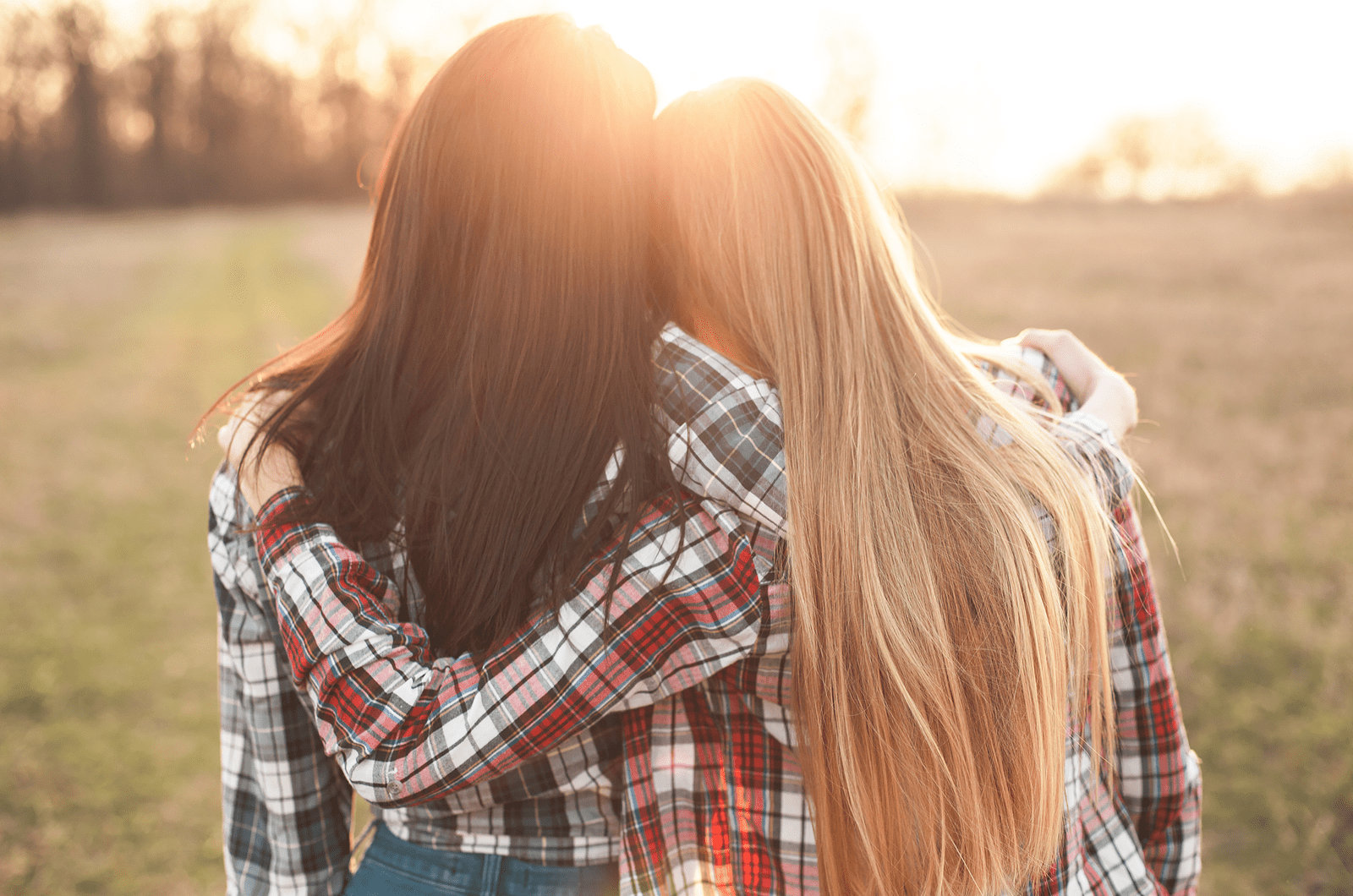 Two young woman looking on the sunset and hugging