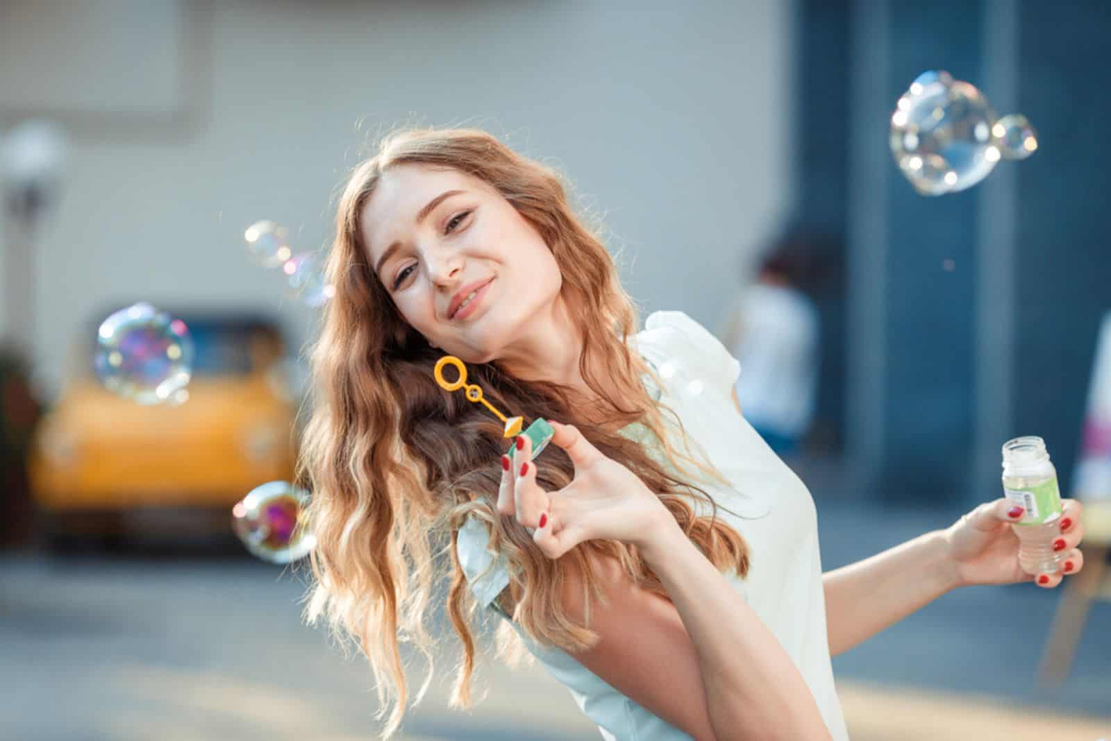 happy beautiful woman blowing soap bubbles outdoor
