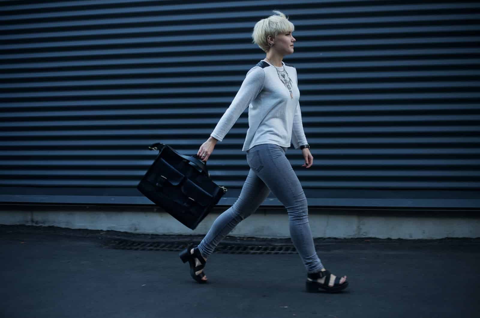 short woman walking and carrying a bag