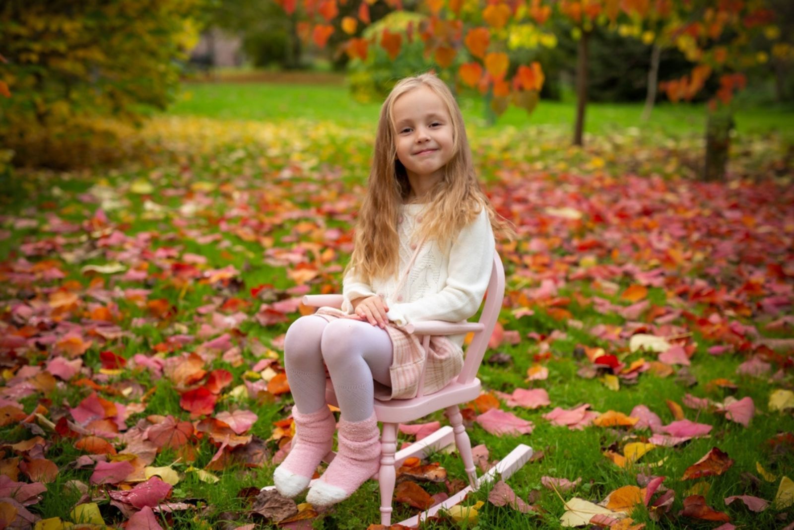 Cute little girl on a swing chair in an autumn garden
