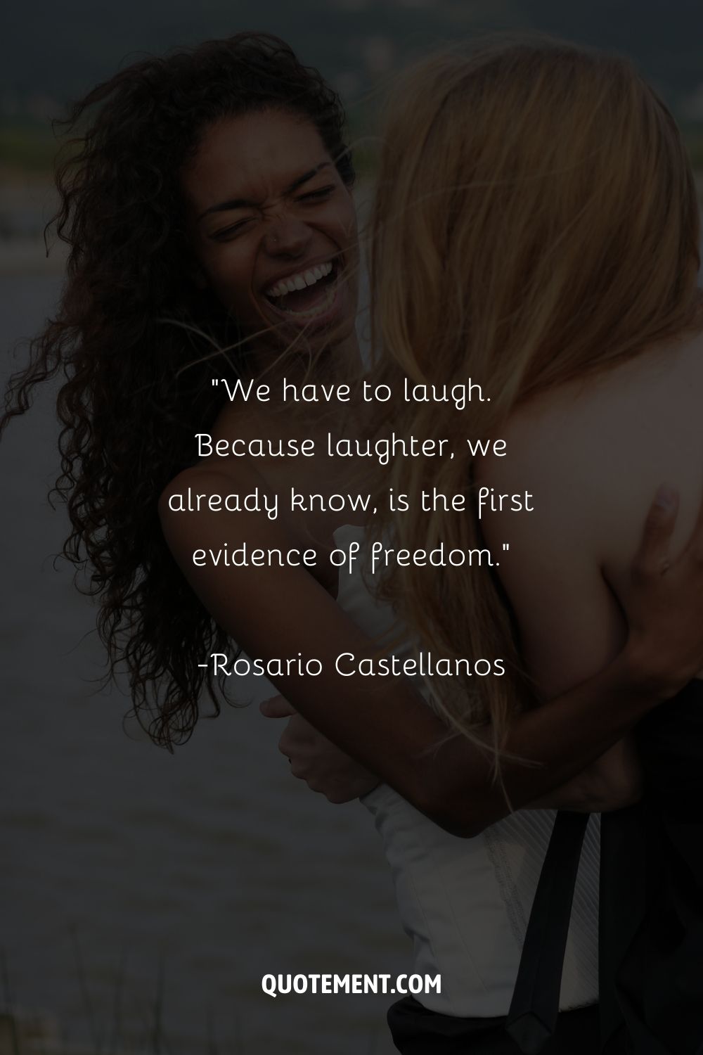 two girls hugging and laughing by the sea