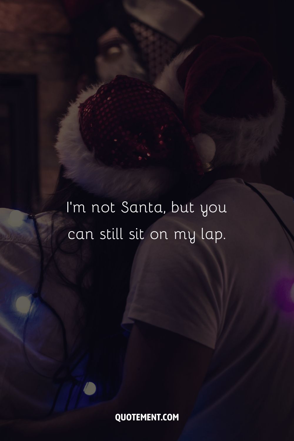 A back view of a couple in Santa's hats with Christmas lights glowing around them