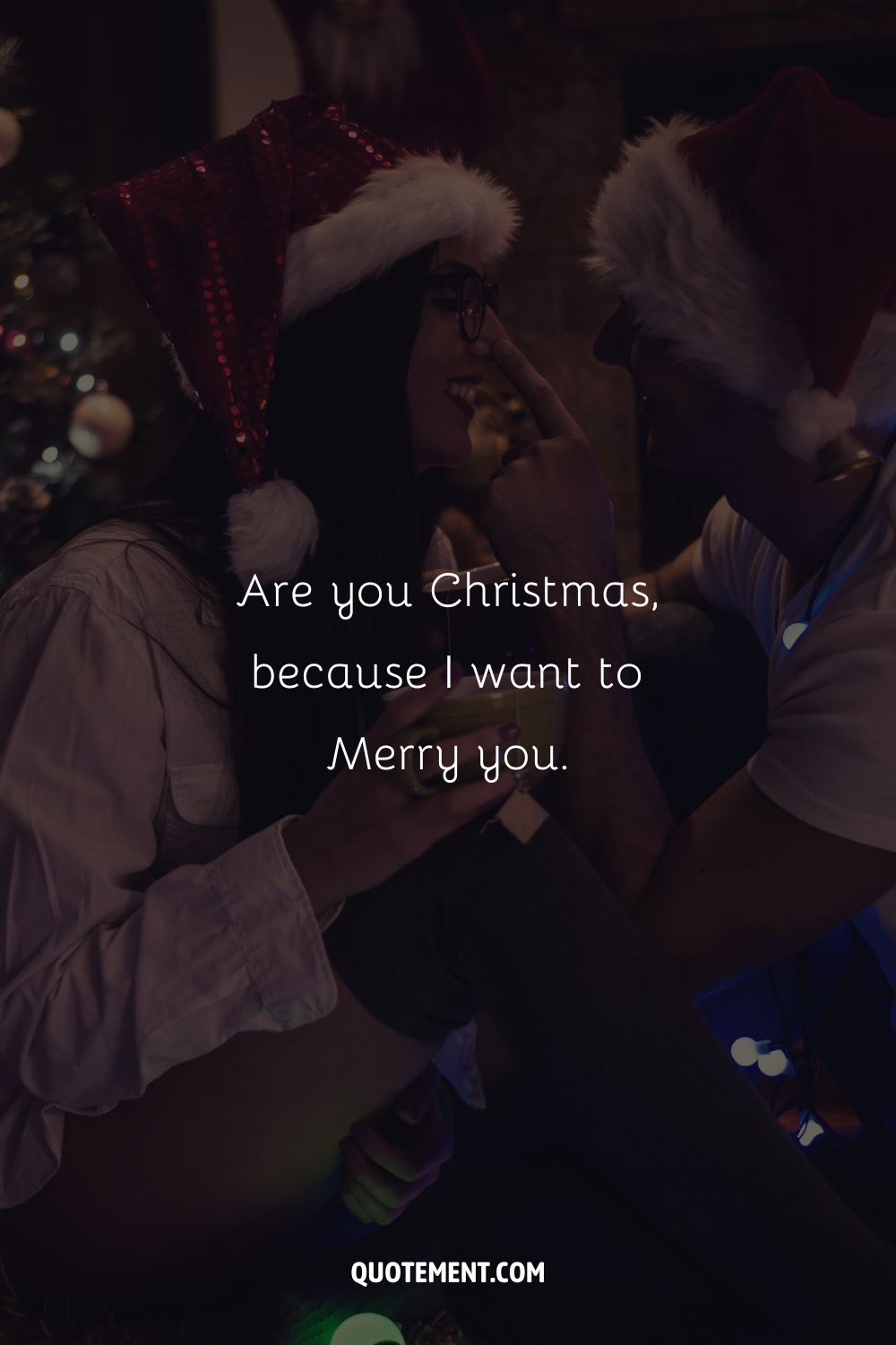 A close-up of a couple wearing Santa hats and sitting close together