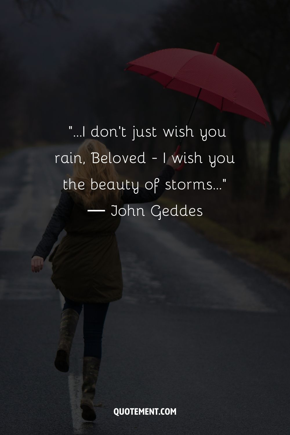 A blonde woman striding along a foggy road with an open umbrella in hand
