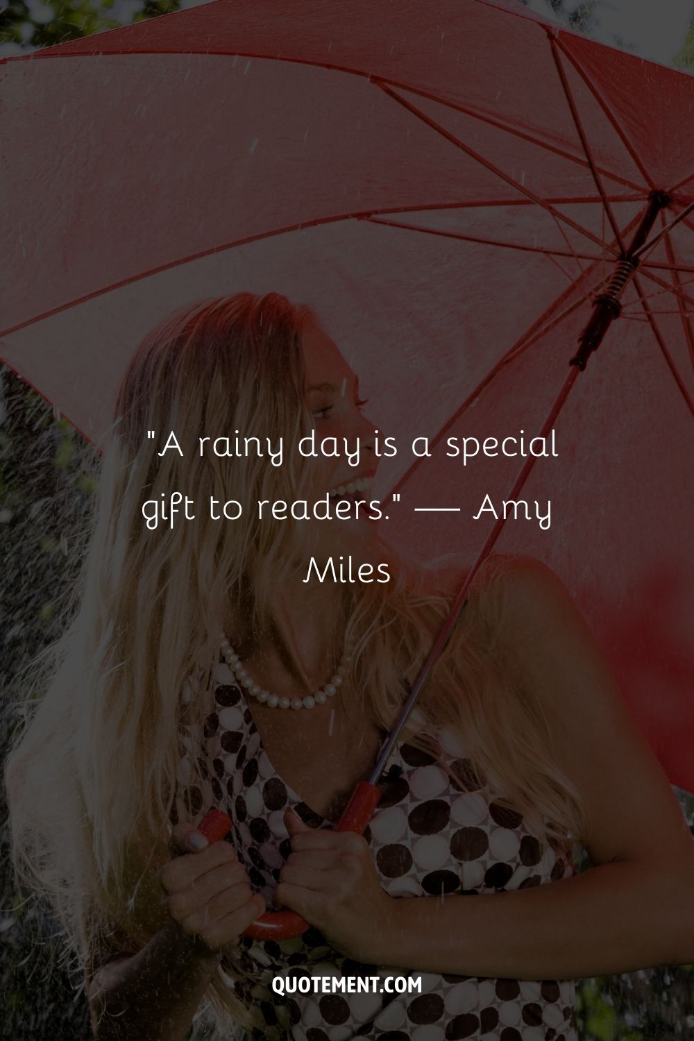 A smiling woman holding a red umbrella sheltering herself from the rain
