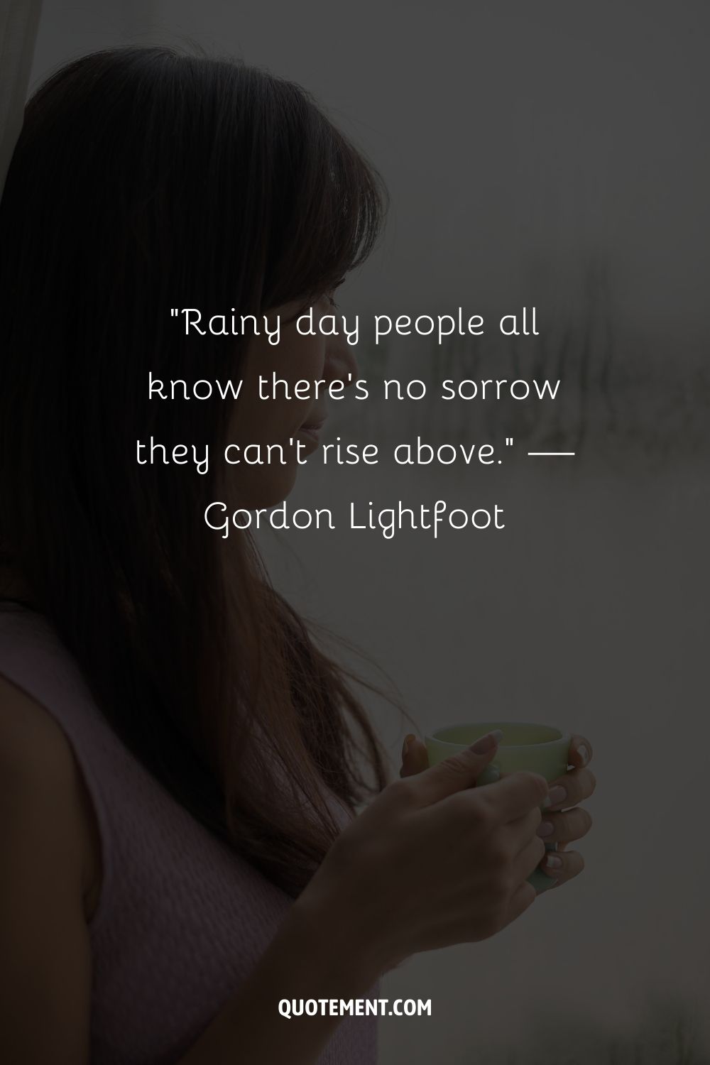 A young woman with a mug in hand beside a wet window
