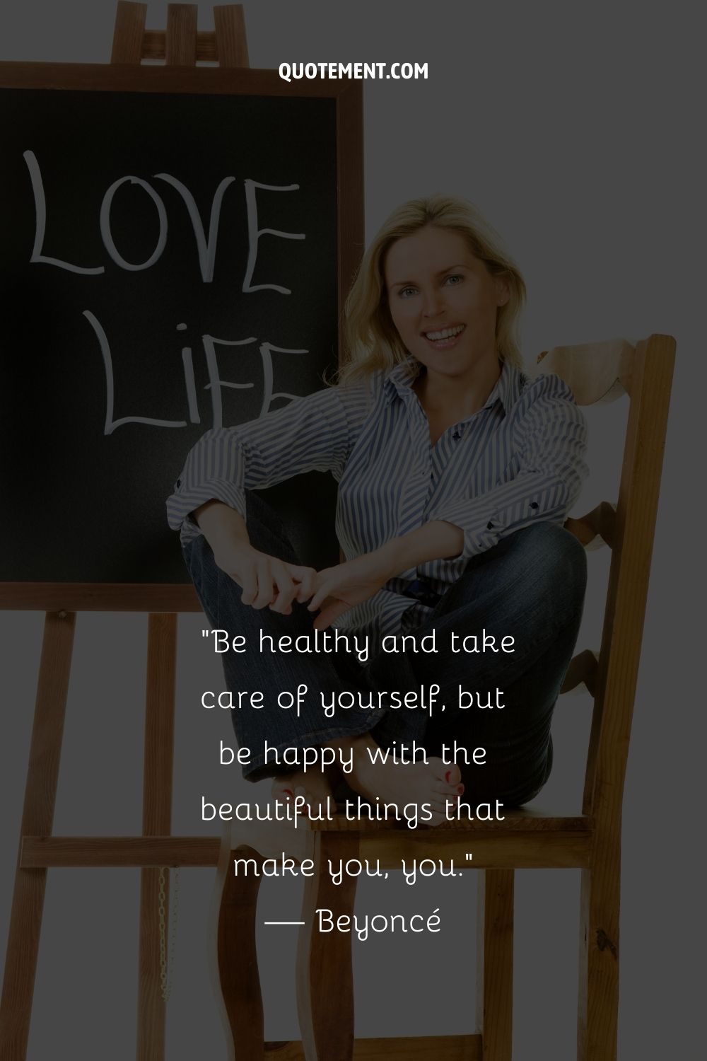 A smiling blonde woman sitting on a chair next to a board